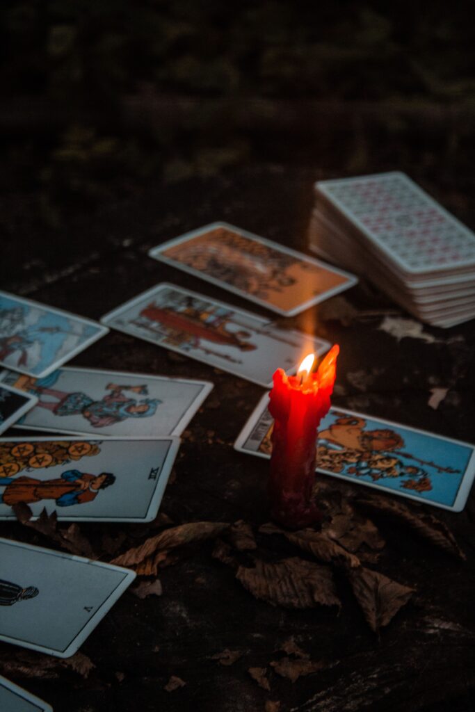 Atmospheric shot of tarot cards with a burning red candle, creating a mystical ambiance.