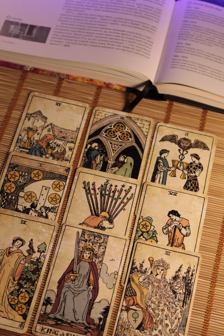 Vintage tarot cards arranged on a bamboo mat with an open book nearby.